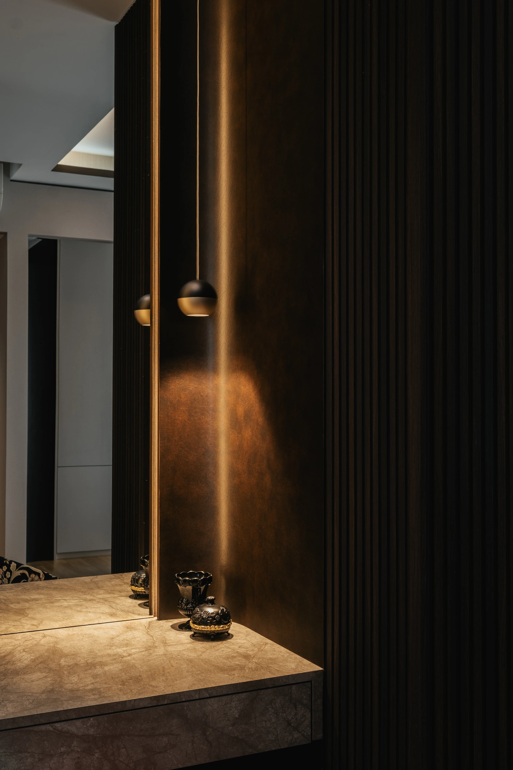 Stone-topped vanity recessed into dark fluted joinery by Edgeline Planners