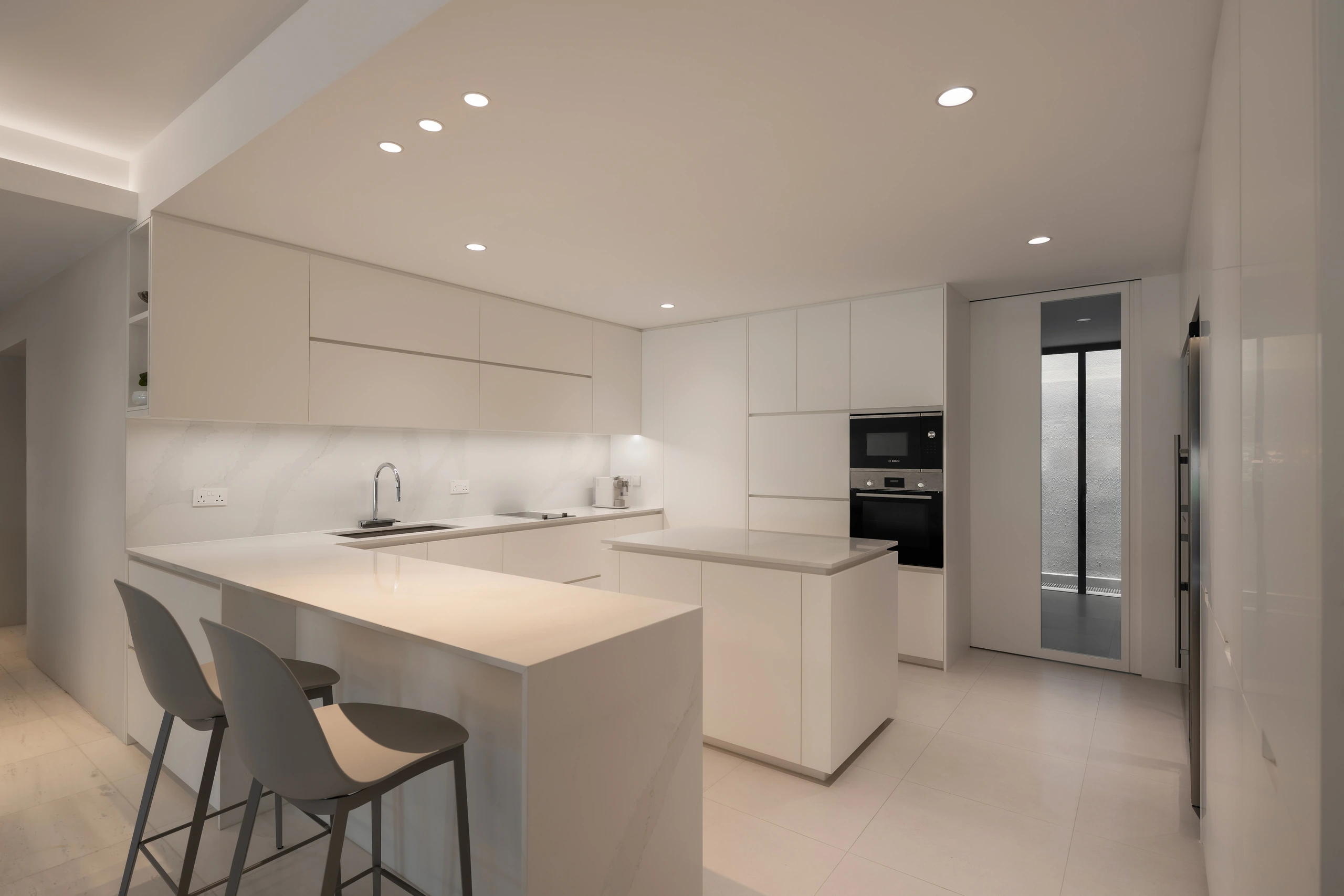 Open dry kitchen with island and concealed storage by Edgeline Planners