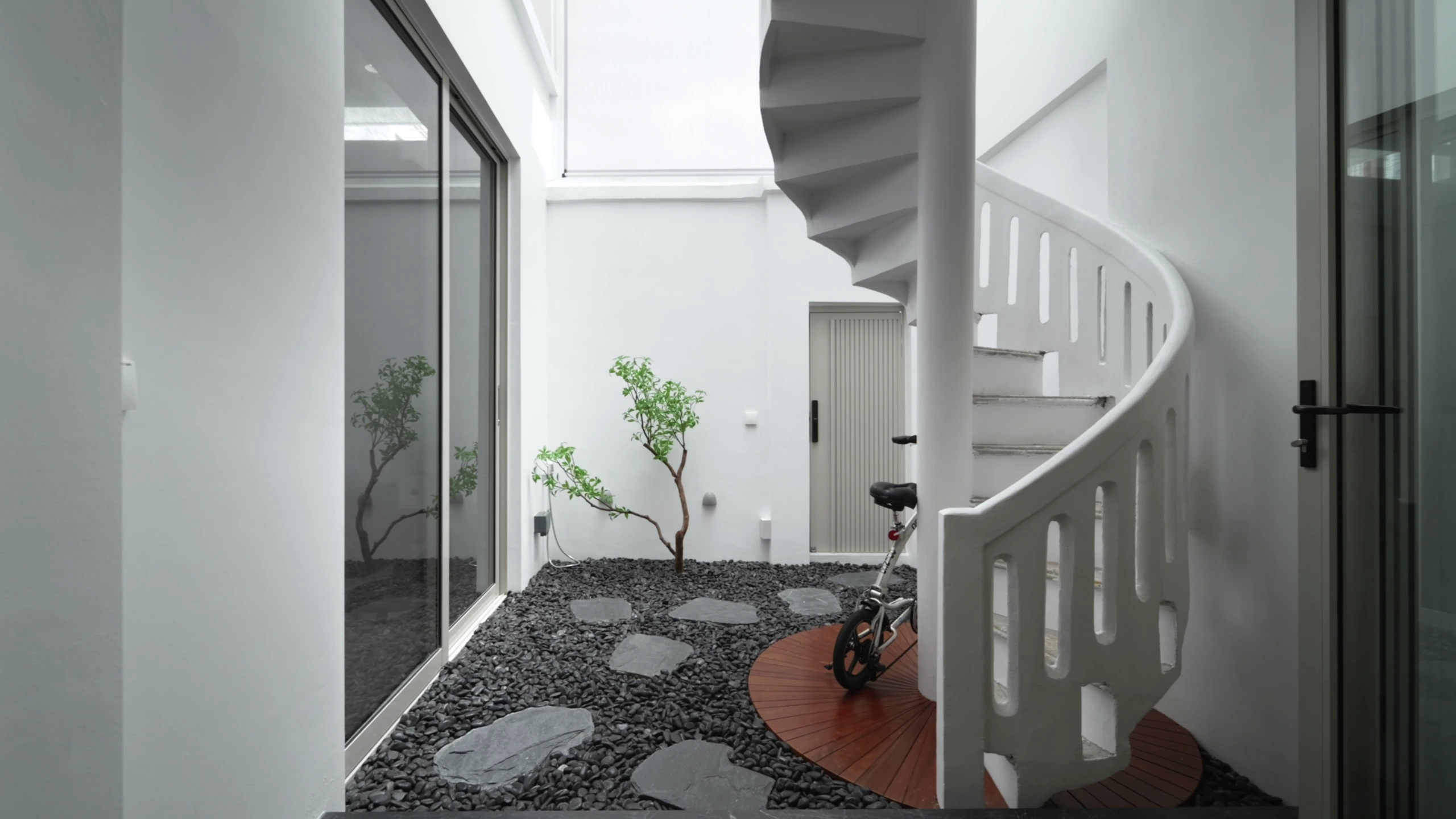 Courtyard with pebble garden and white spiral staircase by Edgeline Planners