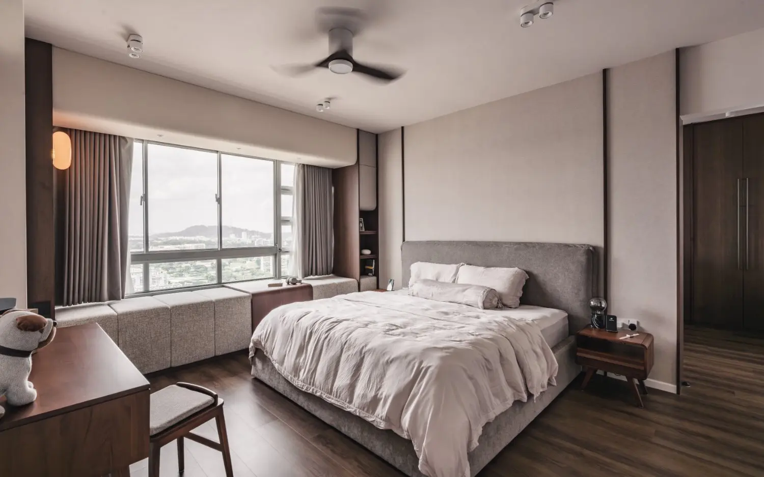 Master bedroom with upholstered bed, bay window and dark timber joinery