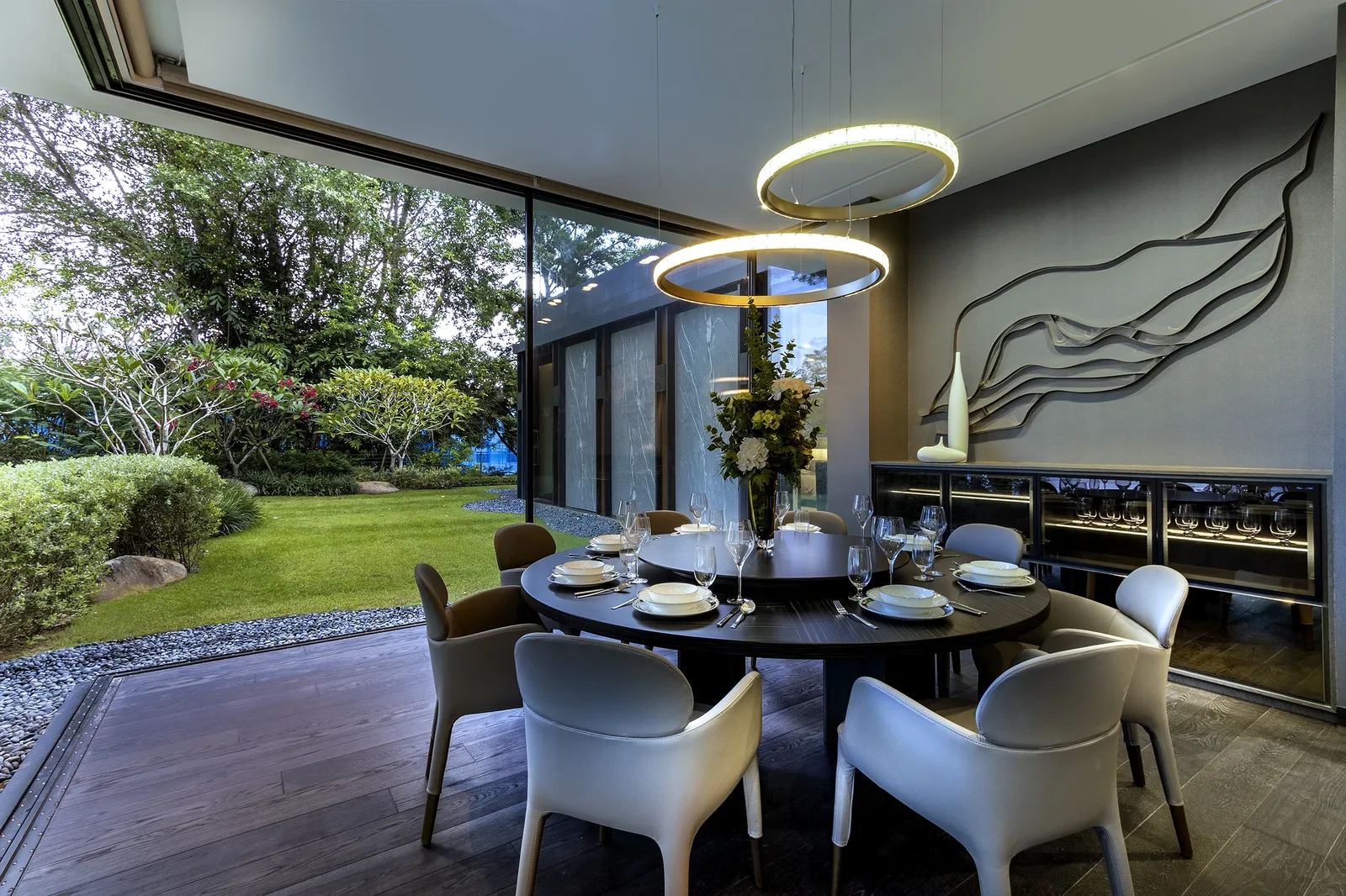 SuMisura &mdash; eight-seater round dining table with lazy Susan, ring chandelier and garden view