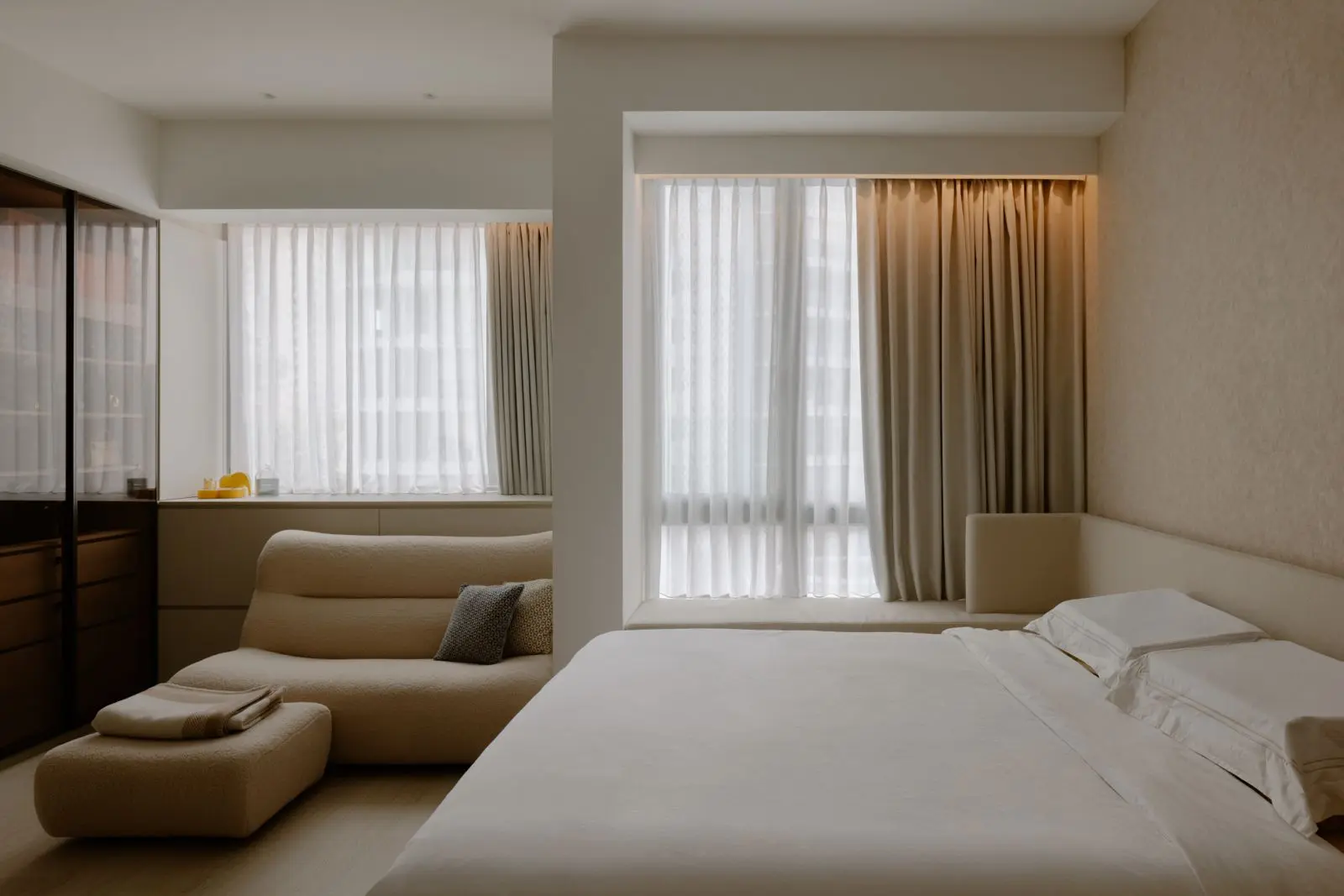 Master bedroom with curved lounge chair and full-height windows